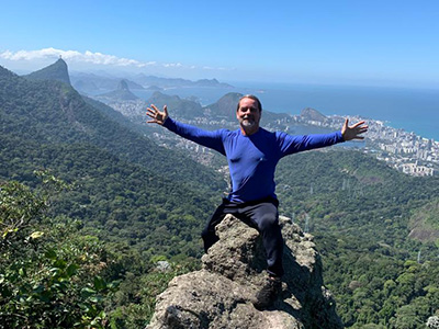 Tour Guide Gus on top of a rock in front of the landscape of Rio de Janeiro.